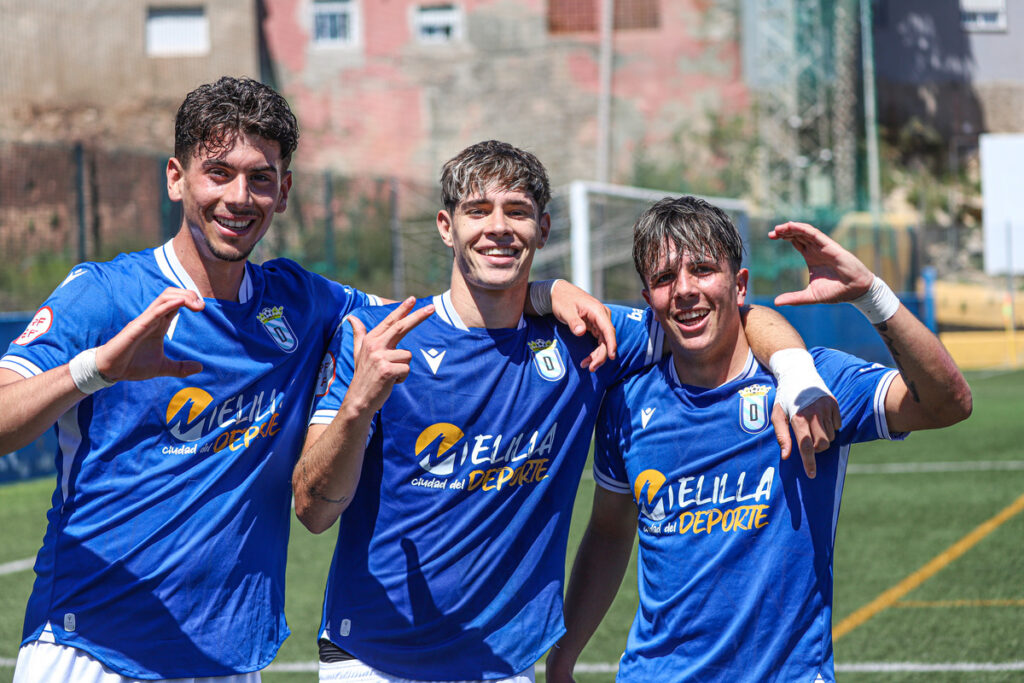 Tres jugadores de fútbol sonriendo y celebrando en el campo