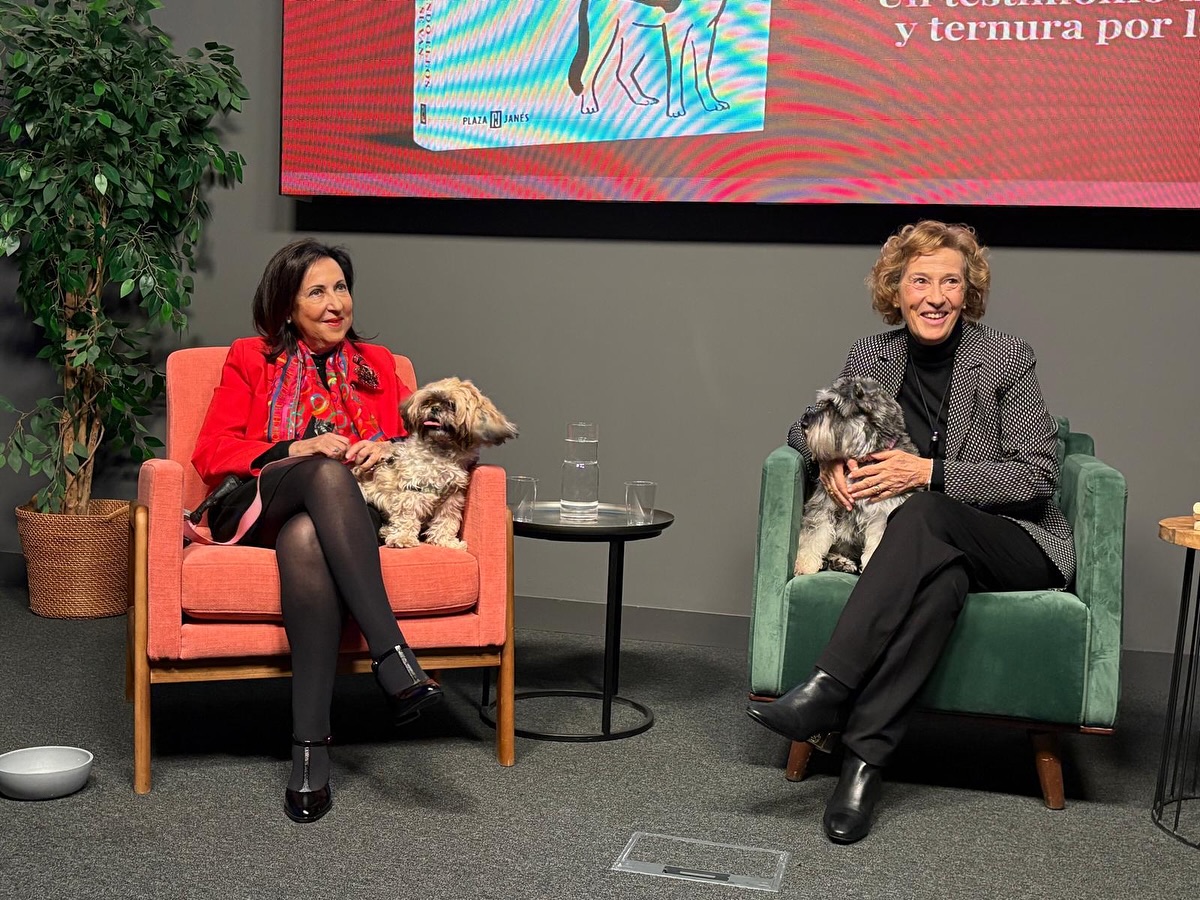 Julia Navarro y otra mujer sentadas con perros en un evento