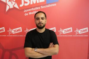 Retrato de un joven con camiseta negra frente a un fondo rojo