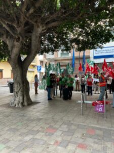 Grupo de personas con banderas en una manifestación bajo un árbol