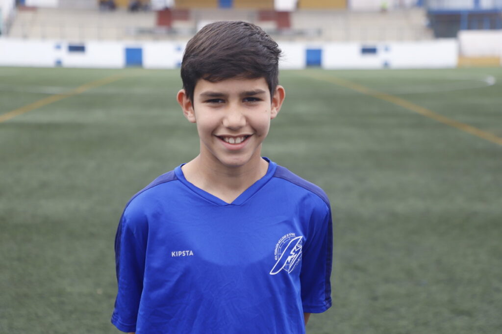 Niño sonriente en uniforme de fútbol en el campo