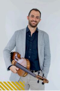 Músico sonriente sosteniendo un violín en un fondo claro