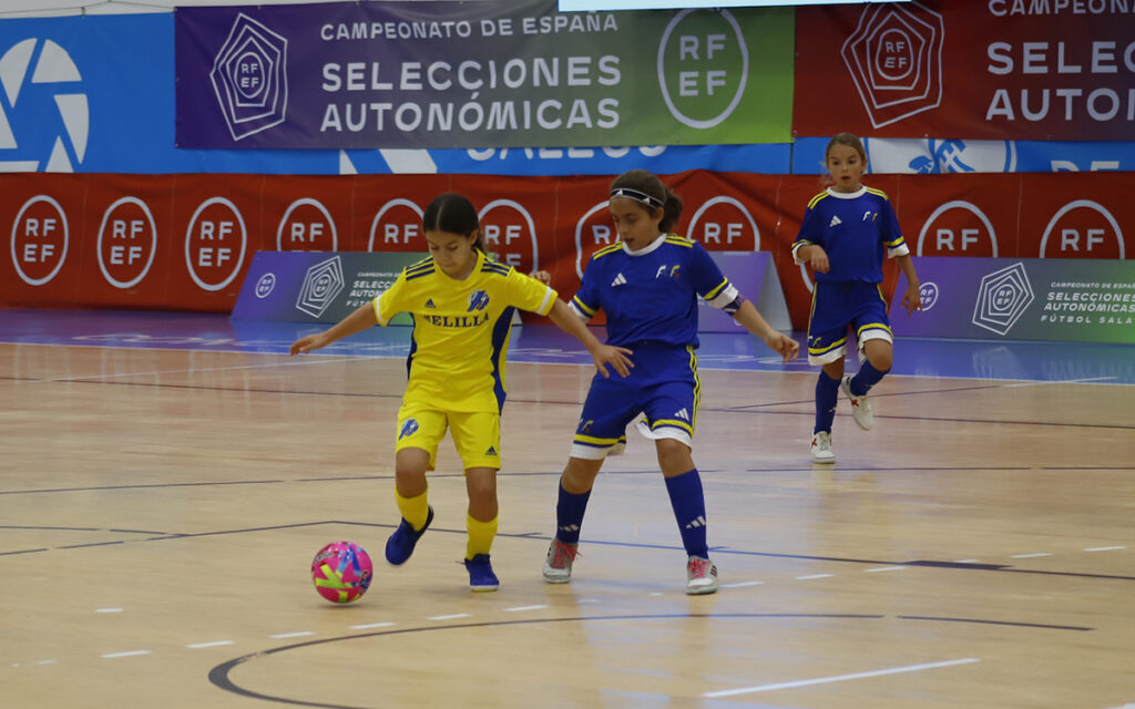 Niña en uniforme azul celebra un gol en un partido de fútbol sala