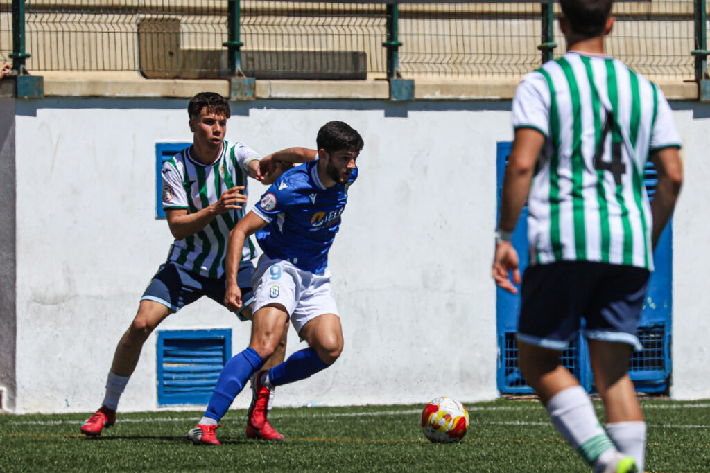 Dos jugadores de fútbol compiten en un partido en el campo.