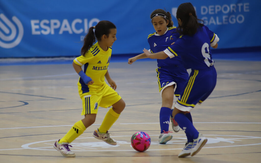 Niños jugando al fútbol en una cancha interior durante un partido