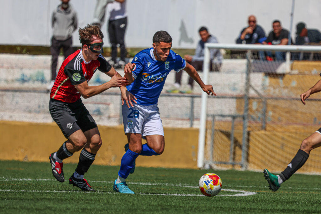 Jugadores de fútbol en acción durante un partido entre U.D. Melilla y U.D. San Pedro.