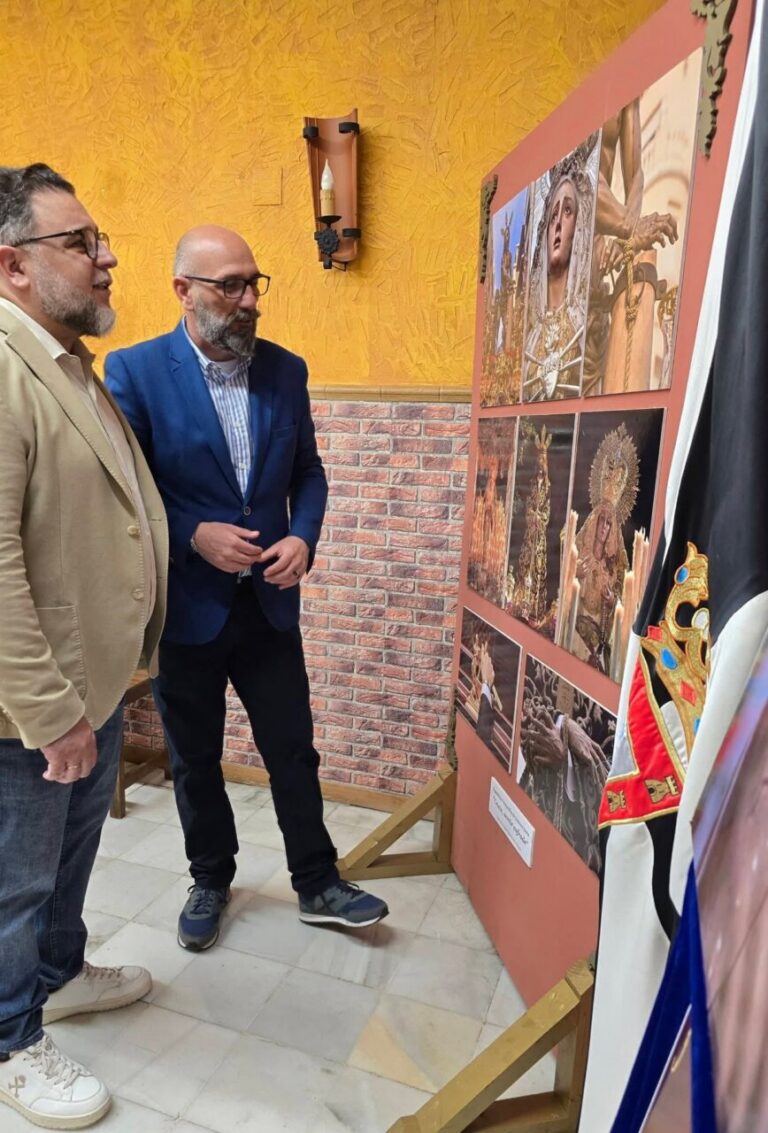 Dos hombres observando una exposición fotográfica sobre la Semana Santa.