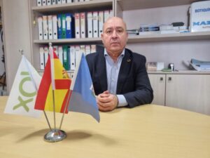 Hombre sentado en una mesa con banderas en primer plano