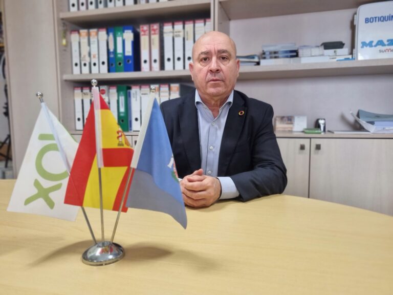 Hombre sentado en una mesa con banderas en primer plano