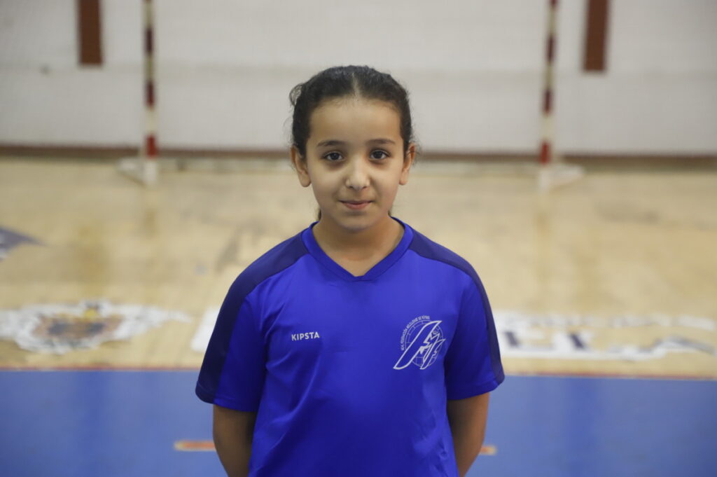 Niña en camiseta azul en un gimnasio de fútbol sala