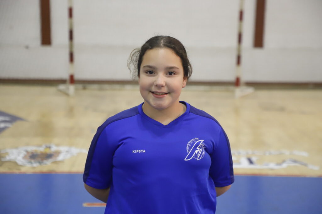 Niña sonriente con camiseta azul en una cancha de fútbol sala