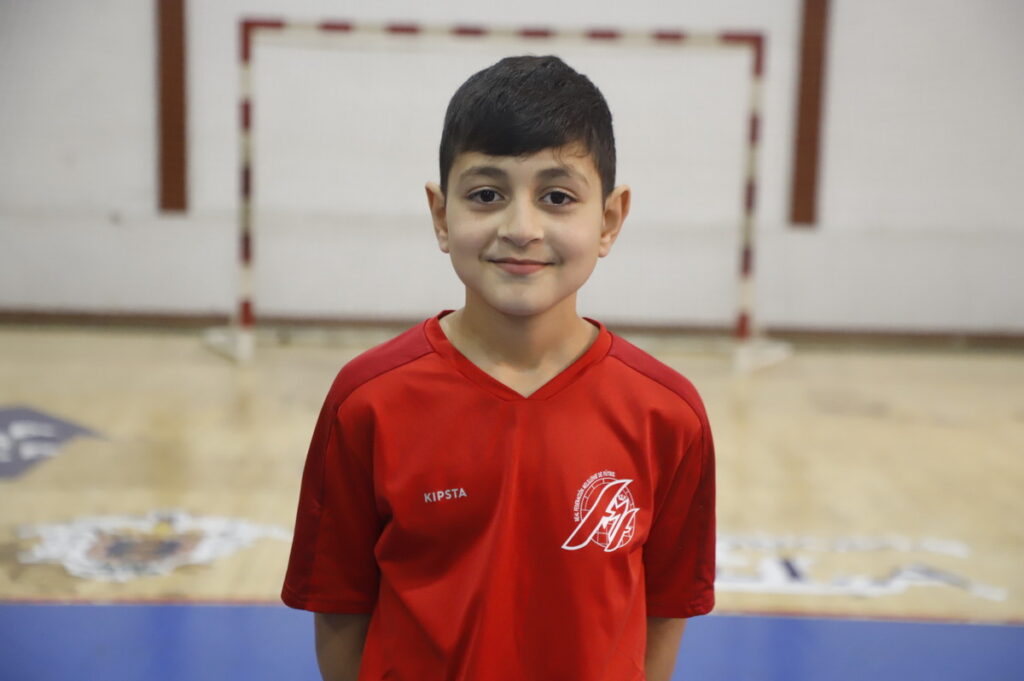 Niño sonriente en camiseta roja en un campo de fútbol