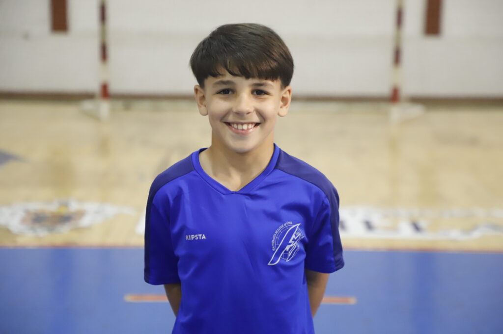 Niño sonriente en camiseta azul en un gimnasio