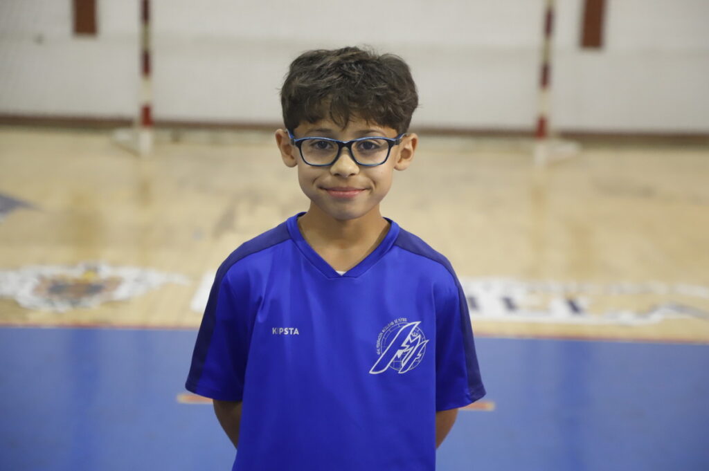Niño sonriente con gafas en un gimnasio deportivo