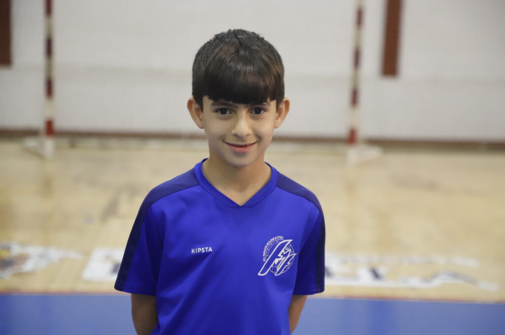 Niño sonriente con camiseta azul en un gimnasio