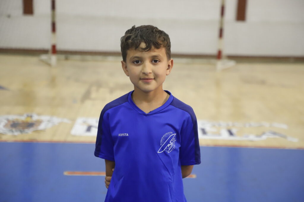 Niño sonriente con camiseta azul en un gimnasio de fútbol
