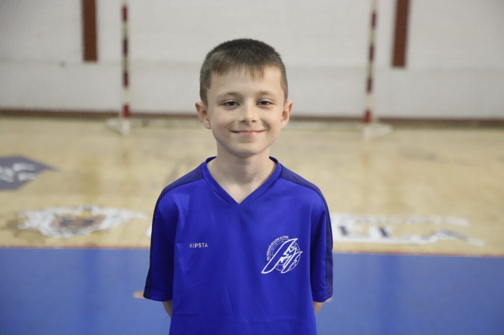 Niño sonriente con camiseta azul en un gimnasio