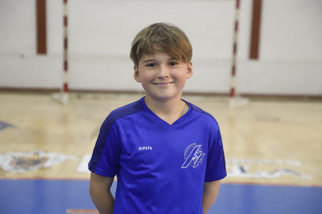 Niño sonriente con camiseta azul en un gimnasio