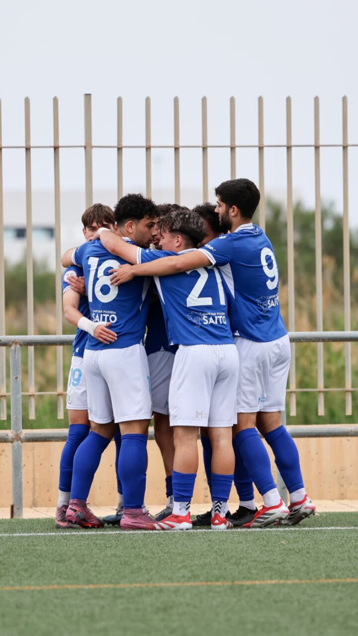 Blue-clad soccer players form a tight huddle on the field, arms around each other in celebration or strategy.
