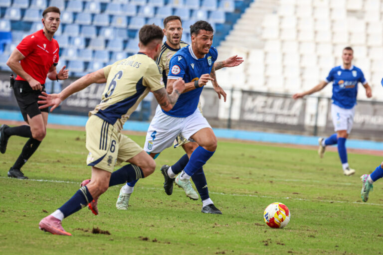 Jugadores de la U.D. Melilla compiten en un partido de fútbol.
