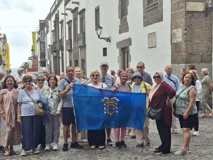 Grupo de personas mayores sosteniendo una bandera en una calle de Melilla