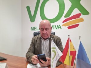 Político de Vox revisando su teléfono en una oficina