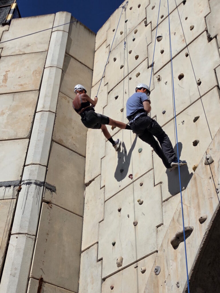 Dos personas escalando en un rocódromo durante un taller de escalada deportiva