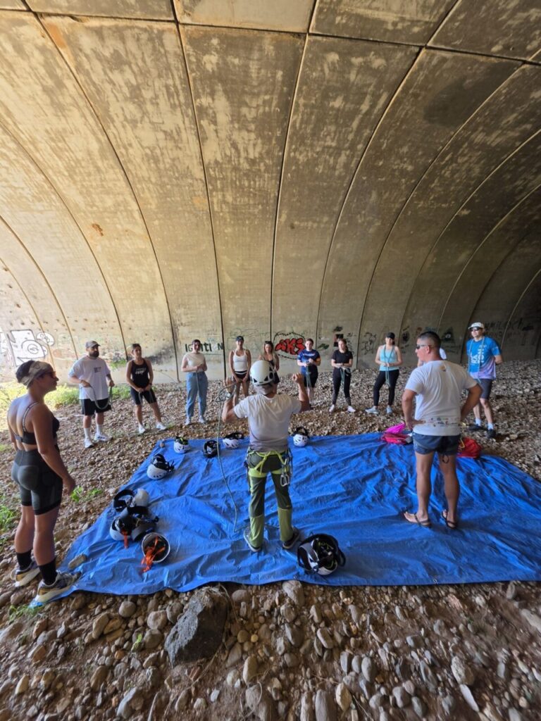 Grupo de personas en un taller de escalada deportiva bajo un puente