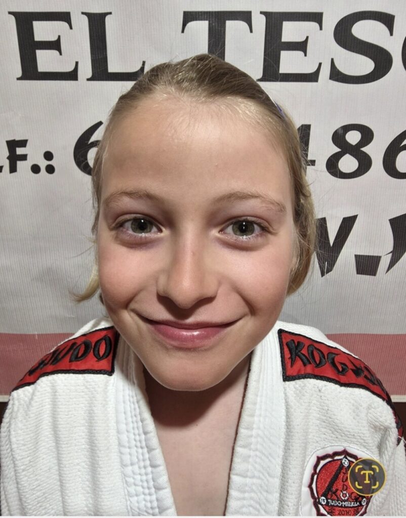 Niña sonriente con uniforme de judo de la Escuela KogyJudo