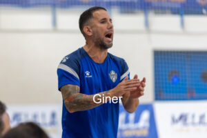 Male athlete in a blue jersey claps during an indoor game, with the name 'Giner' overlaid on the image.
