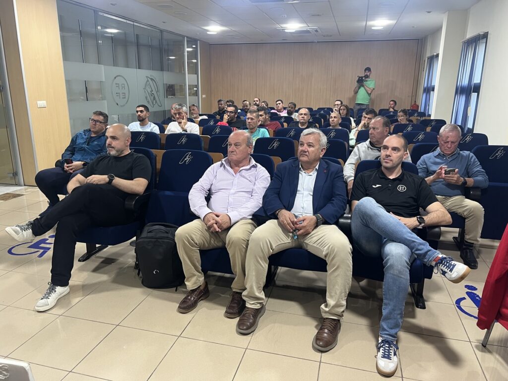 Diverse group of men seated in a conference room, listening to a presentation.