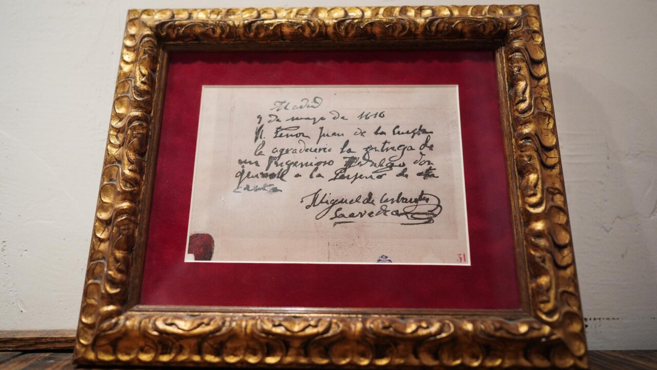 Ornate gold-framed display with a handwritten letter mounted on a burgundy mat.