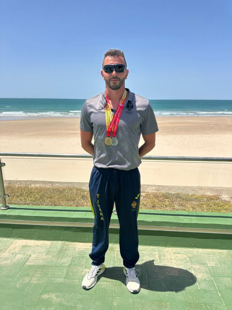 Miguel Ángel Rozas posando con medallas en la playa