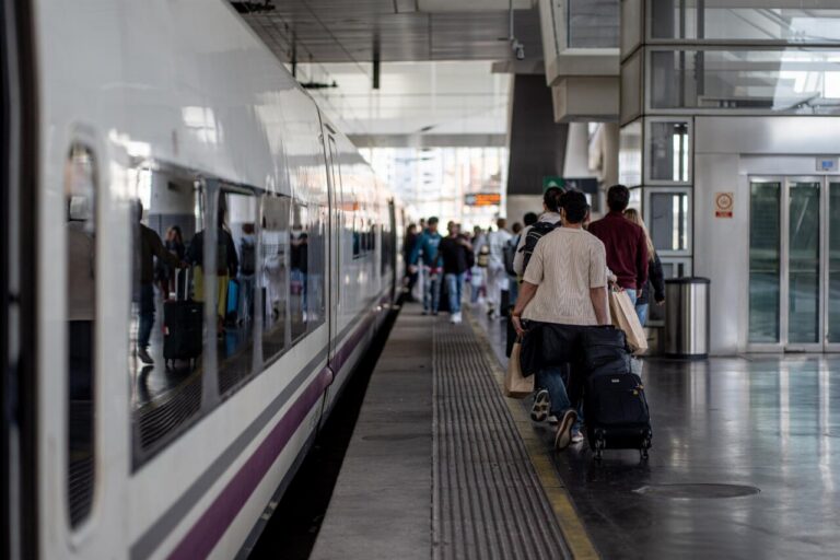 Pasajeros esperando en la estación de tren con maletas