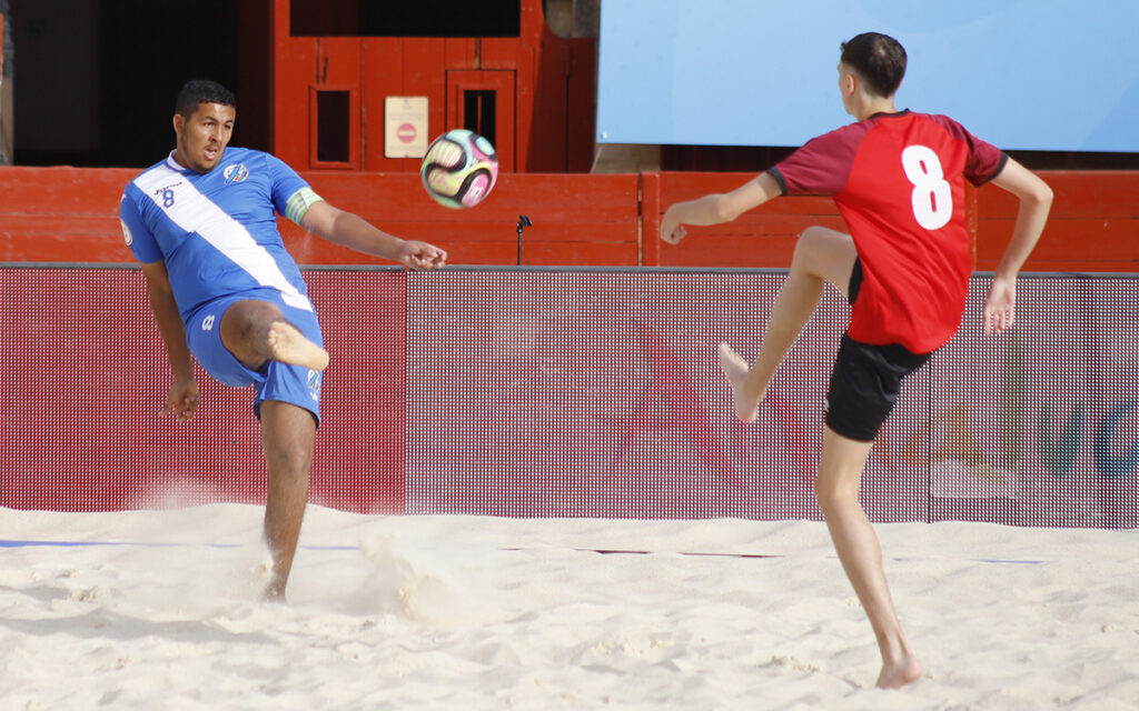 Jugadores de fútbol playa compitiendo en la arena durante un torneo.