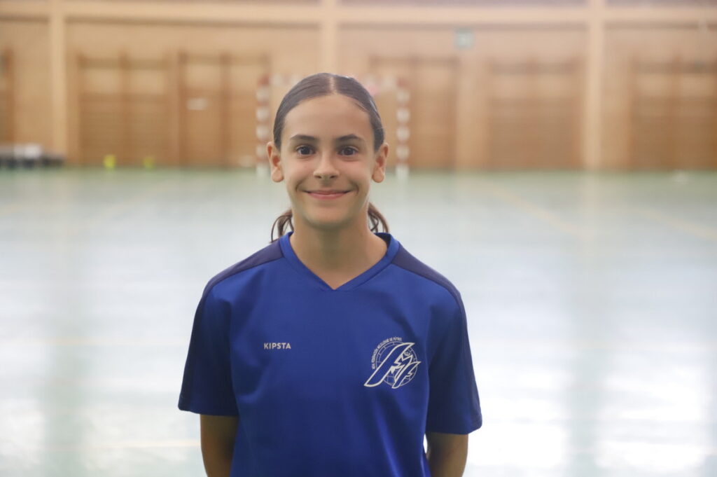 Jugadora de fútbol sala femenino en uniforme azul sonriendo en el pabellón