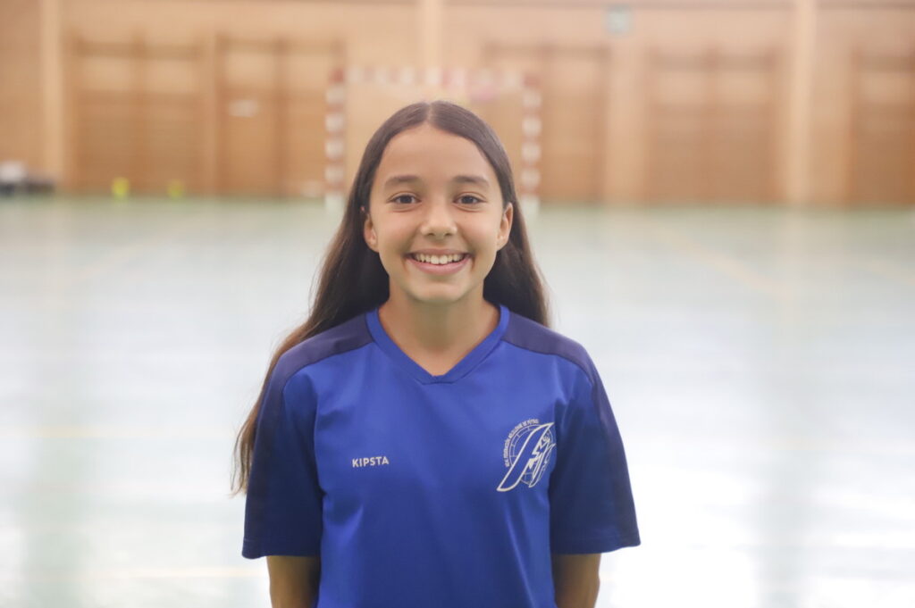 Niña sonriente con camiseta de fútbol sala en un pabellón