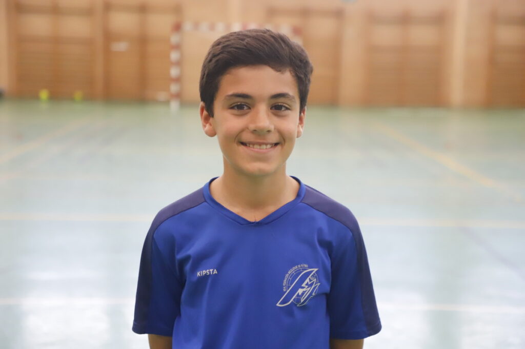 Niño sonriente en camiseta de fútbol sala en un pabellón deportivo