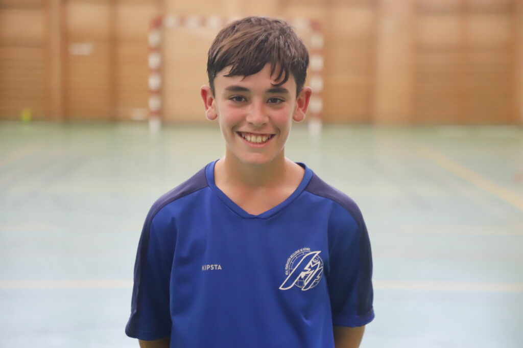 Niño sonriente en camiseta de fútbol sala en un pabellón deportivo