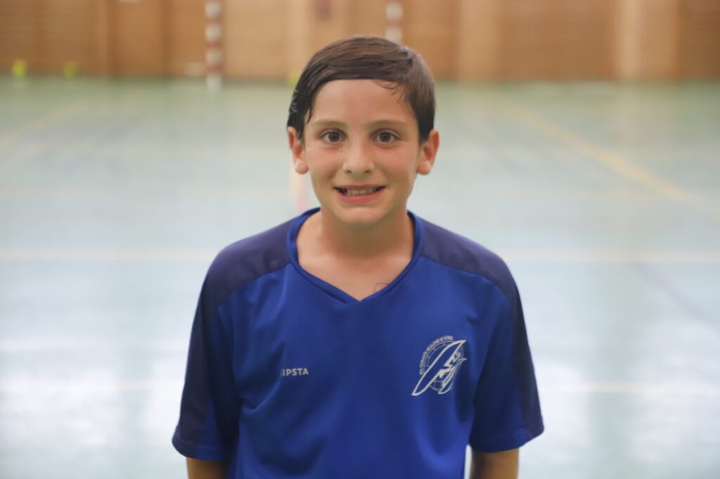 Niño sonriente en camiseta de fútbol sala en un pabellón deportivo