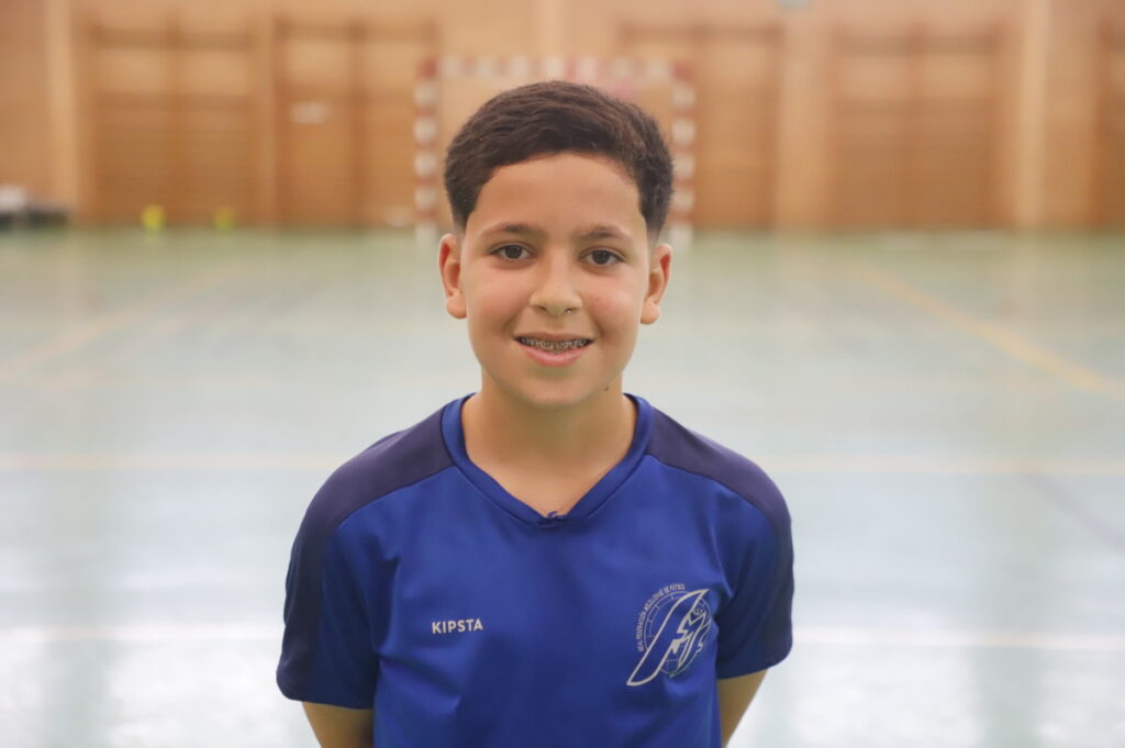 Niño sonriente con camiseta de fútbol sala en un pabellón deportivo