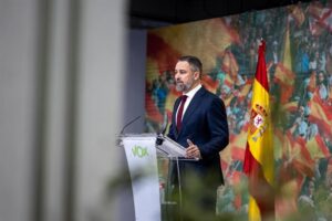 Abascal hablando en un evento de Vox con bandera española de fondo