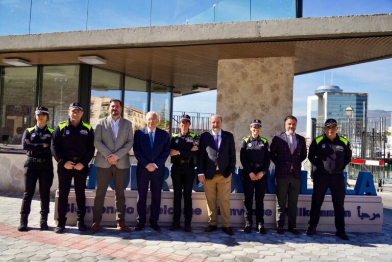 Group of uniformed police officers and suited officials standing in a row for a formal outdoor ceremony outside a modern building.