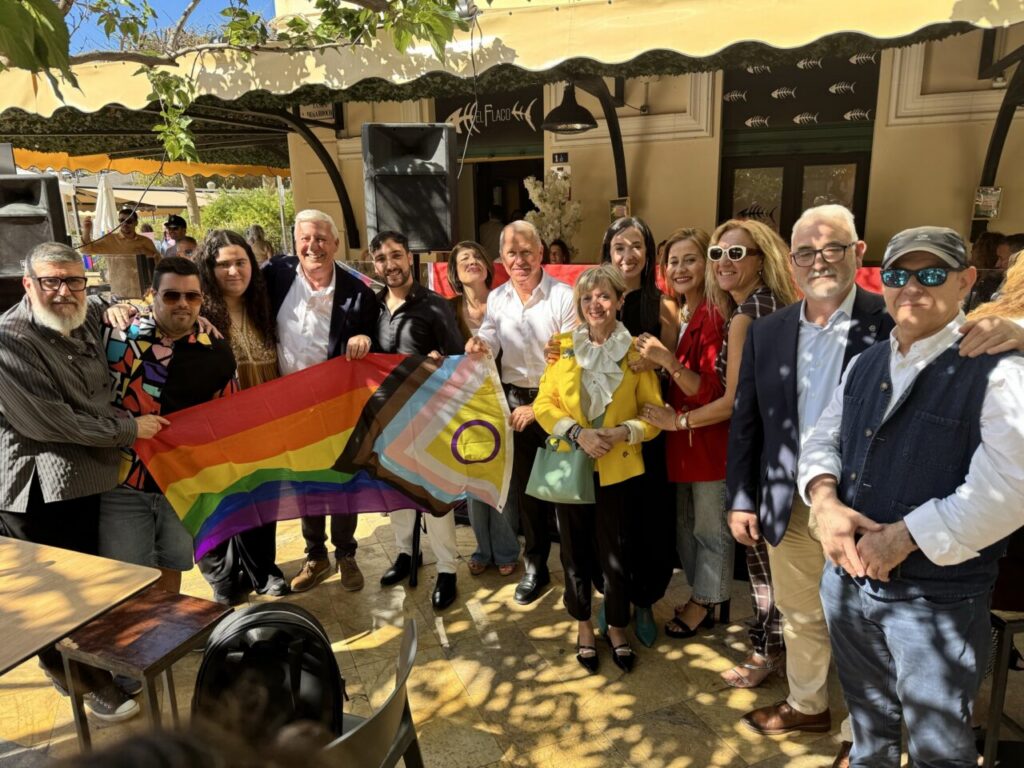 Grupo de personas sosteniendo una bandera del orgullo en un evento de AMLEGA