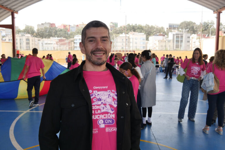 Hombre sonriente en evento educativo con participantes en camisetas rosas