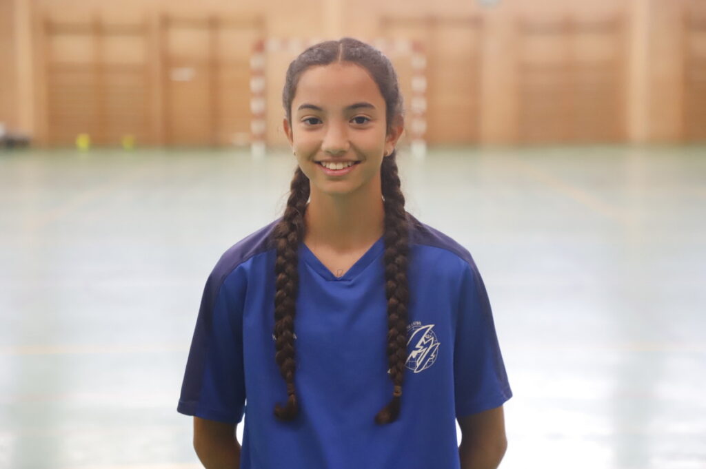 Jugadora de fútbol sala femenino en camiseta azul sonriendo en el pabellón