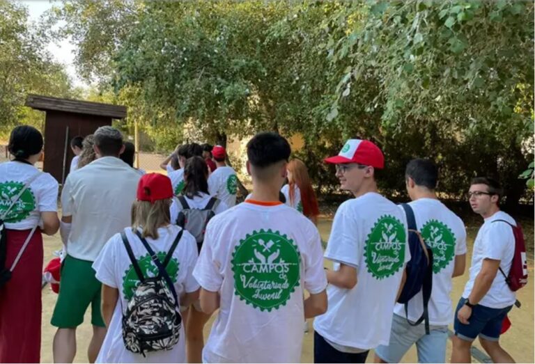Grupo de jóvenes en un campo de voluntariado con camisetas blancas