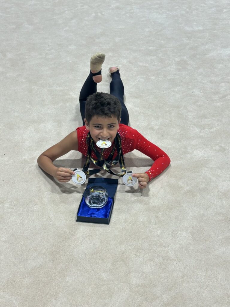 Gimnasta del Club Ágora mostrando medallas y trofeo tras competición