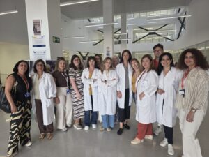 Group of doctors and staff in white coats posing in a bright, modern medical facility lobby.