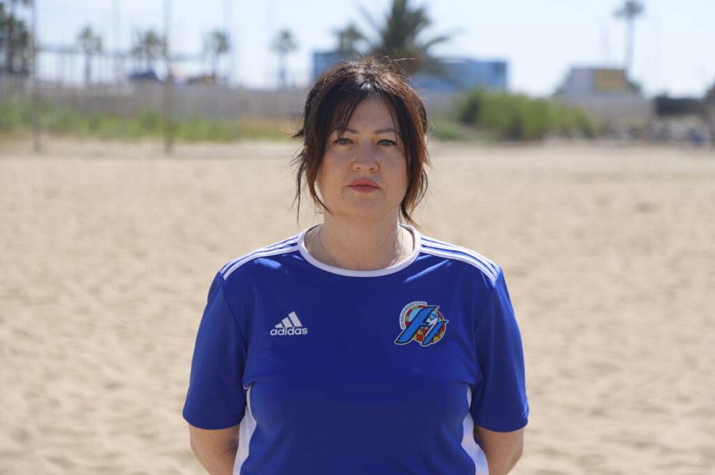 Mujer con camiseta azul en la playa durante un evento deportivo